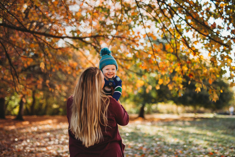 mom and son having fun playing in the leaves at a fall family photoshoot with Roxana Albusel photography